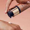 Hand applying a skinbetter Even Intensive skincare serum to arm with a pink background