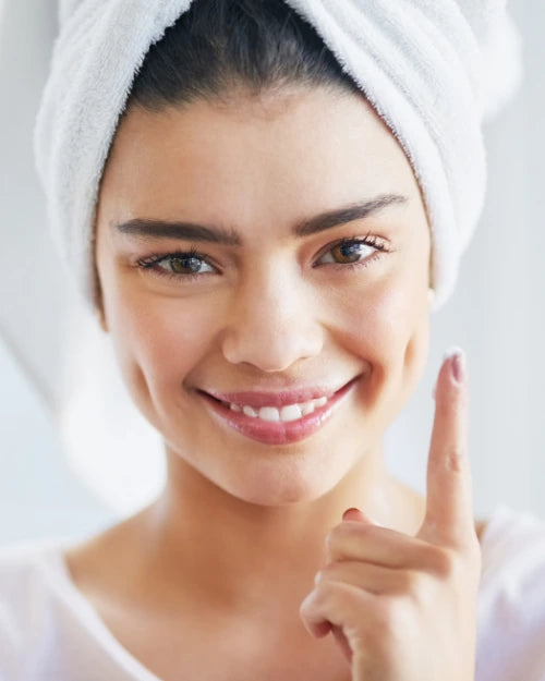 Woman with a towel wrapped around her head doing her skincare routine