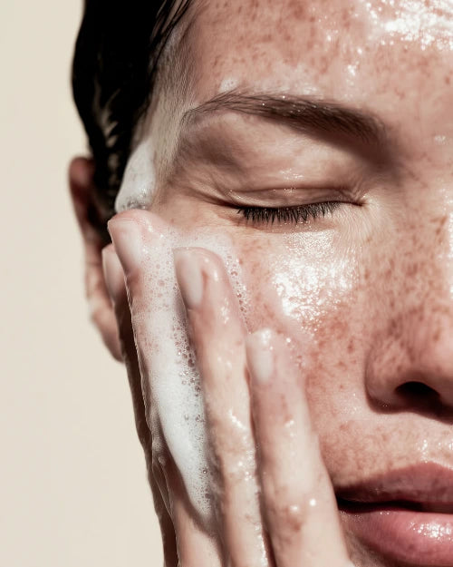Close-up of a person washing their face with foaming face cleanser