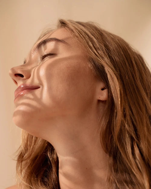 Close-up of a woman with sunlight casting shadows on her face.