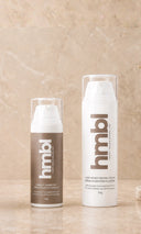 hmbl pigment corrector cream and light moisturizer bottle on a marble background