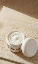 Open jar of cream with 'hmbl' branding on a stone surface