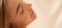 Close-up of a person with closed eyes against a soft beige background