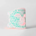 A white Omnilux Contour LED face mask with a mint green floral pattern and pink LED glow, shown on a light gray background.